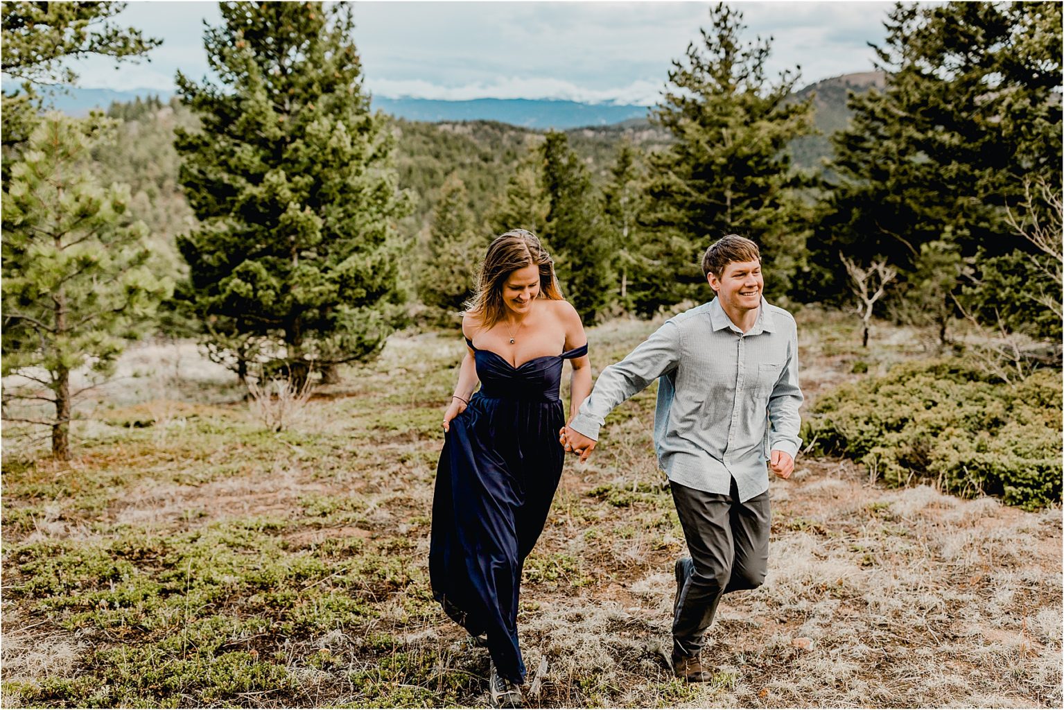 couple with flowy navy dress in boulder Colorado for their hiking engagement session running