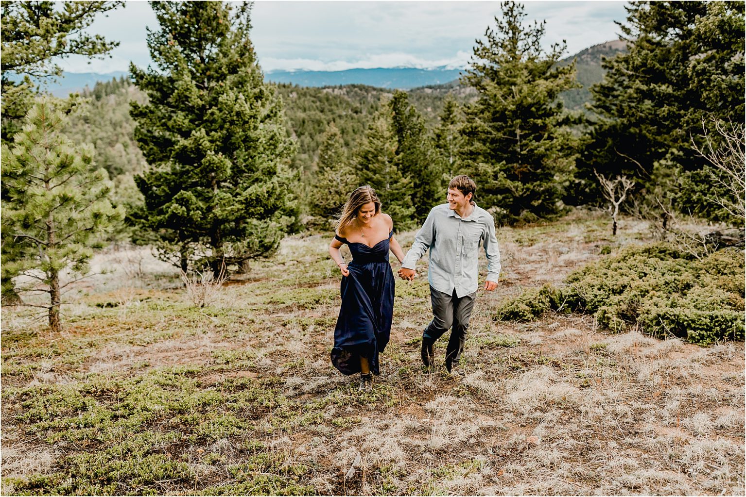 couple with flowy navy dress in boulder Colorado for their hiking engagement session running