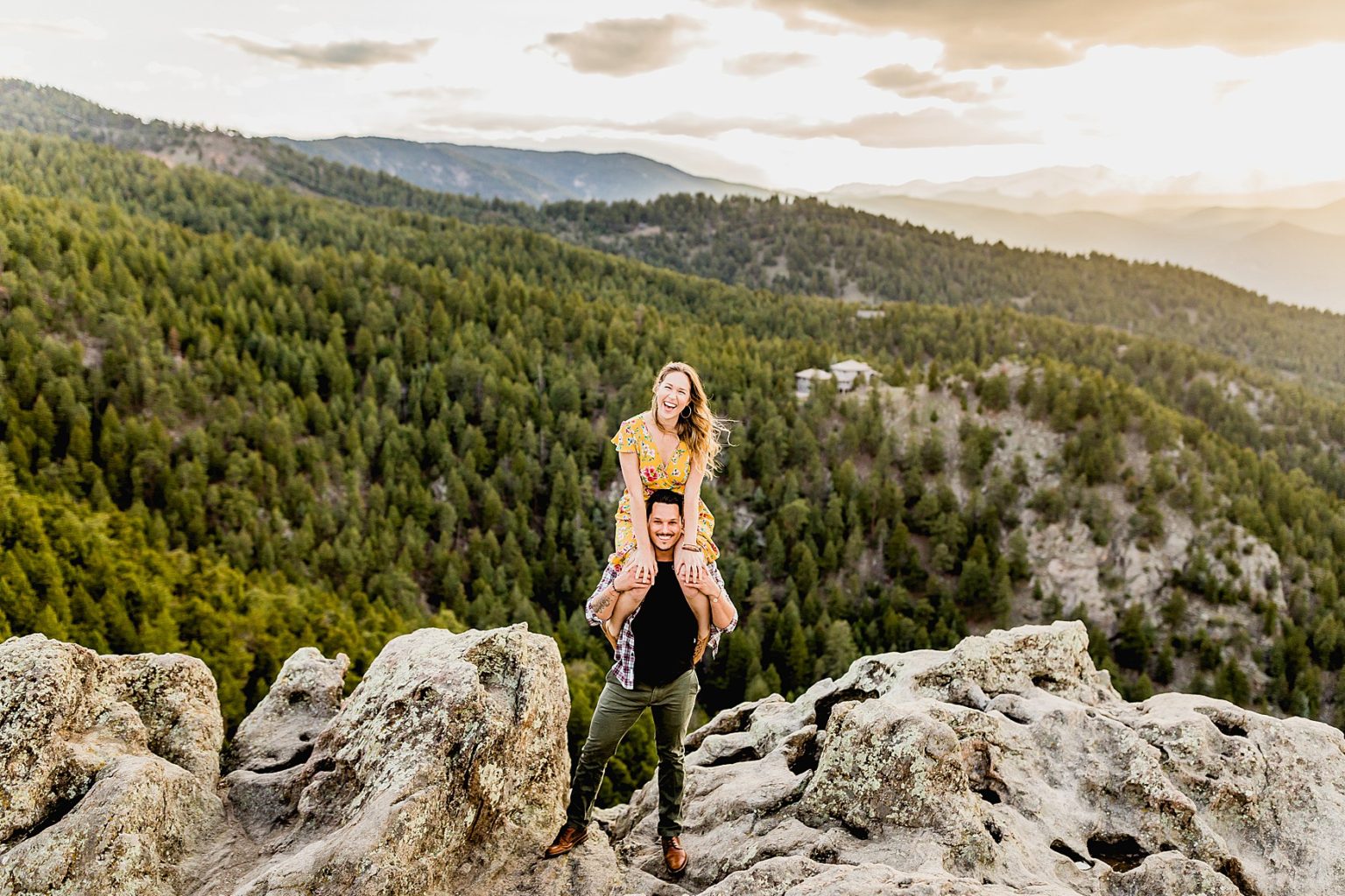 adventurous couple standing in the mountains at lost gulch lookout in boulder colorado for engagement photos with a beautiful mountain background