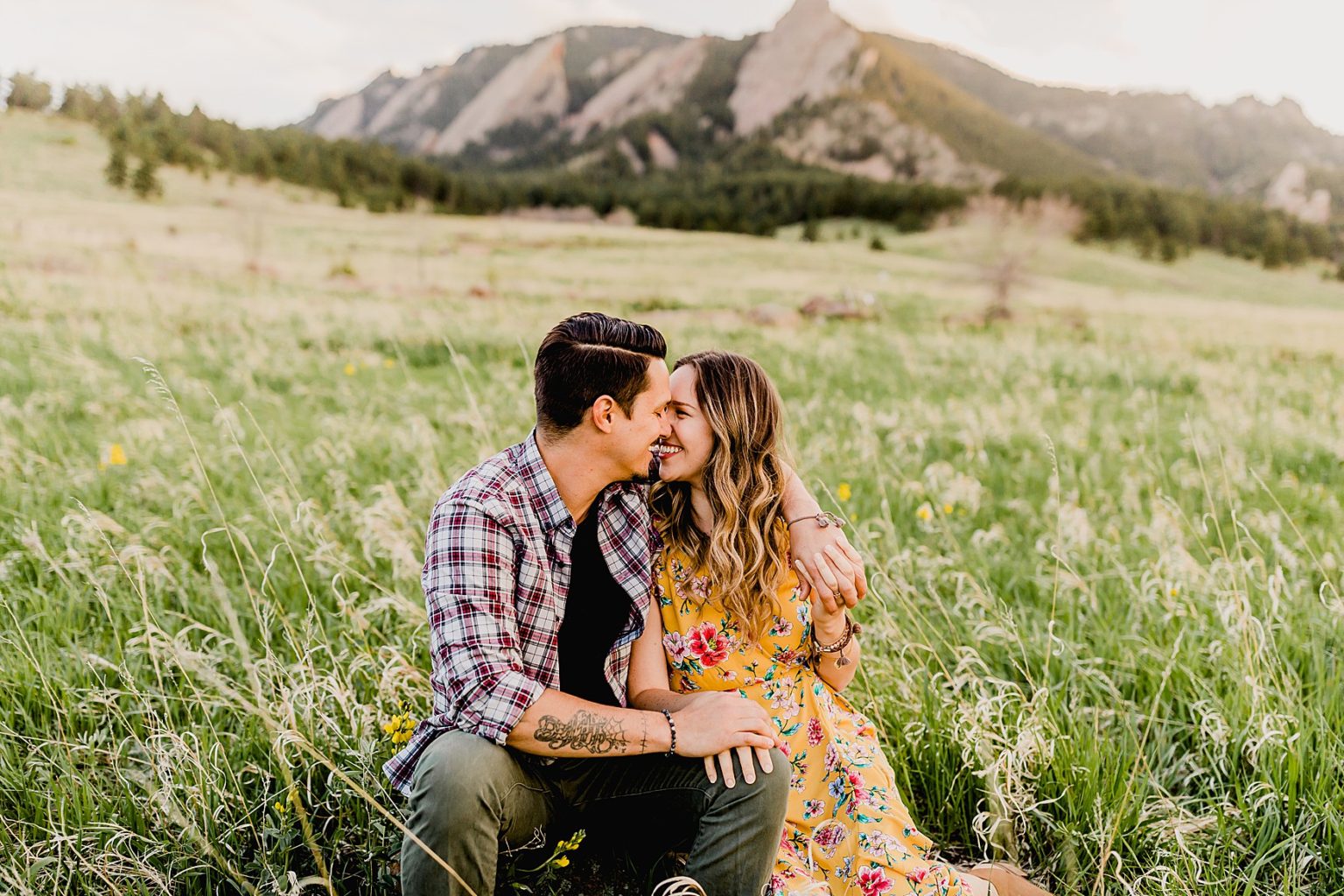 adorable couple sitting in grass at chautauqua park in boulder colorado for their summer engagement photos