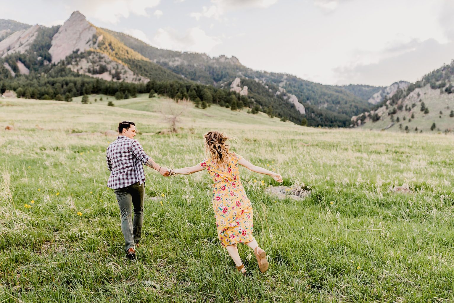 adventurous couple running together at chautauqua park in boulder colorado for their mountain engagement photos including beautiful green scenery