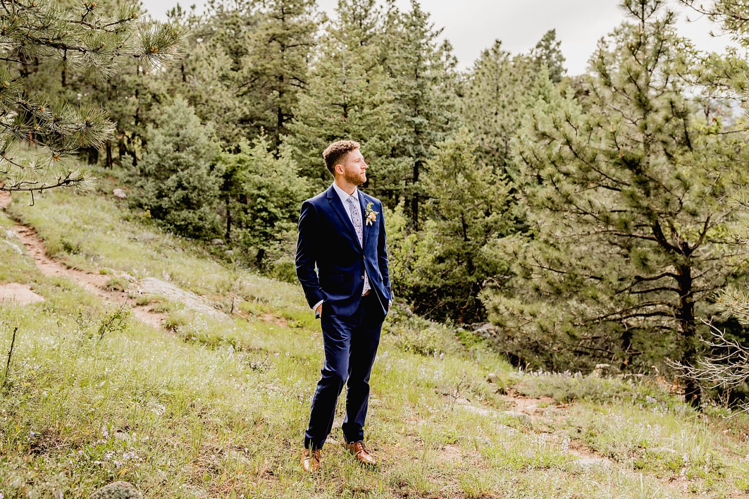 groom stares off into the colorado mountains on his wedding day