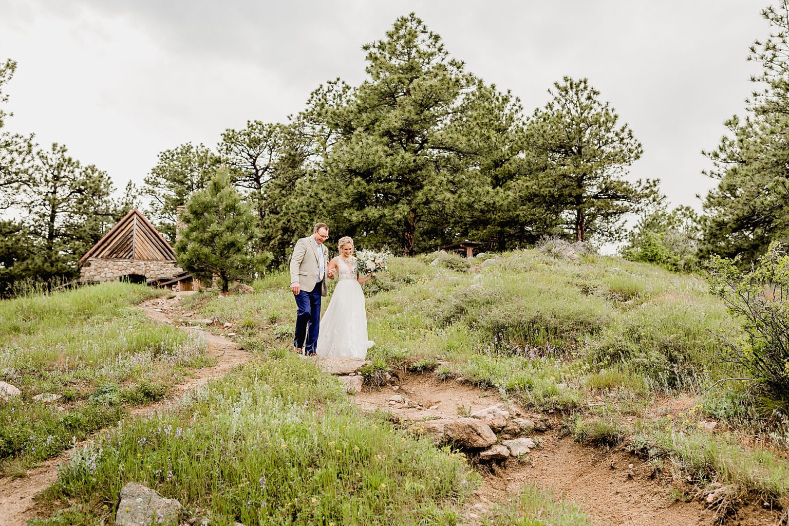 bride and her dad are walking on a path to colorado ceremony
