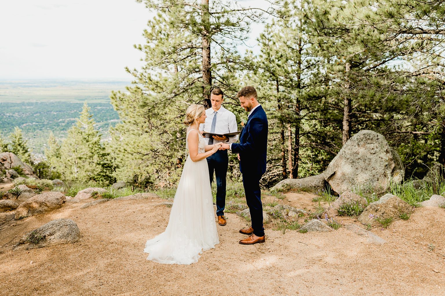 bride and groom exchange rings during their intimate ceremony with views of the boulder mountains in colorado