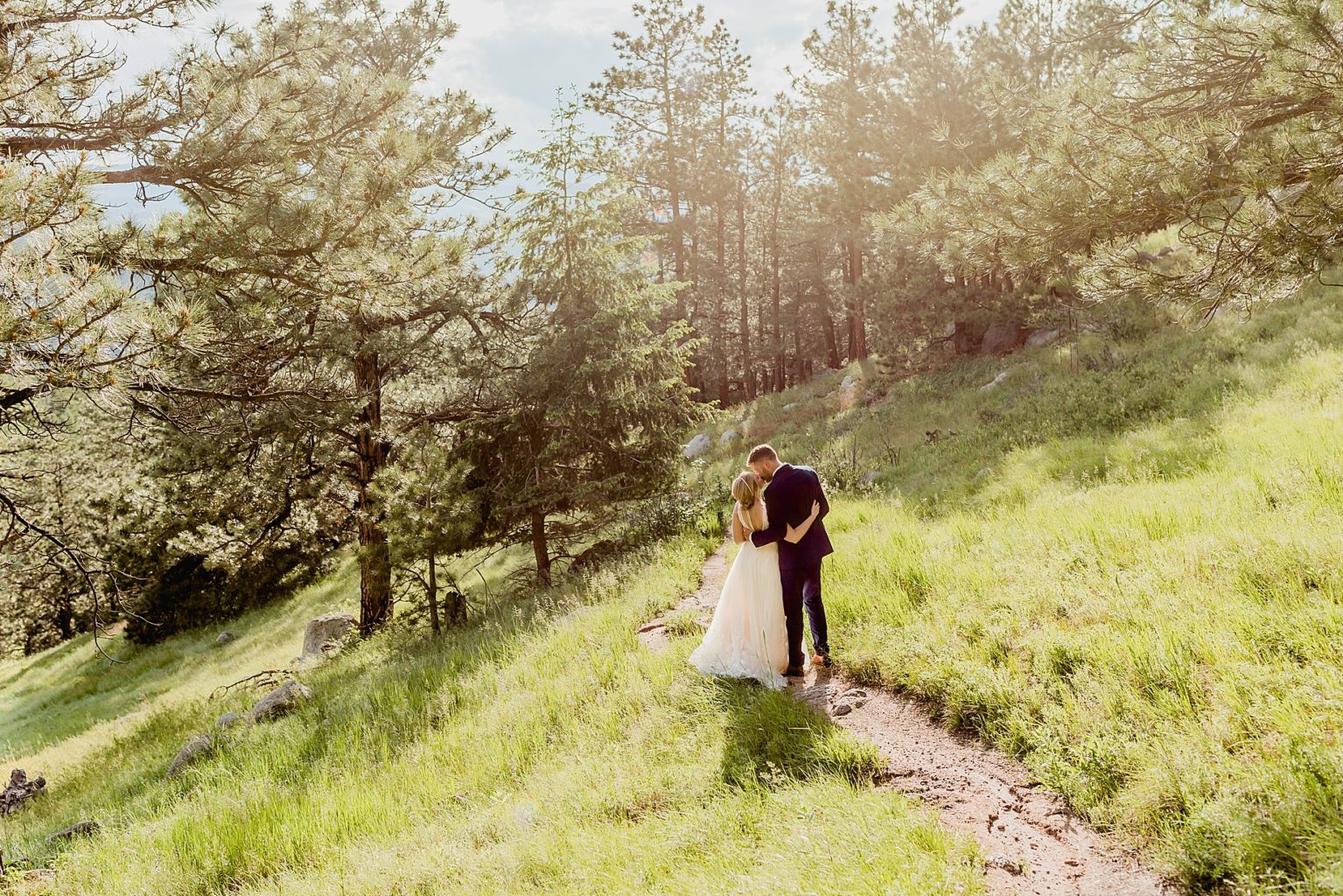 bride and groom begin hiking in the green trees at sunset in boulder colorado