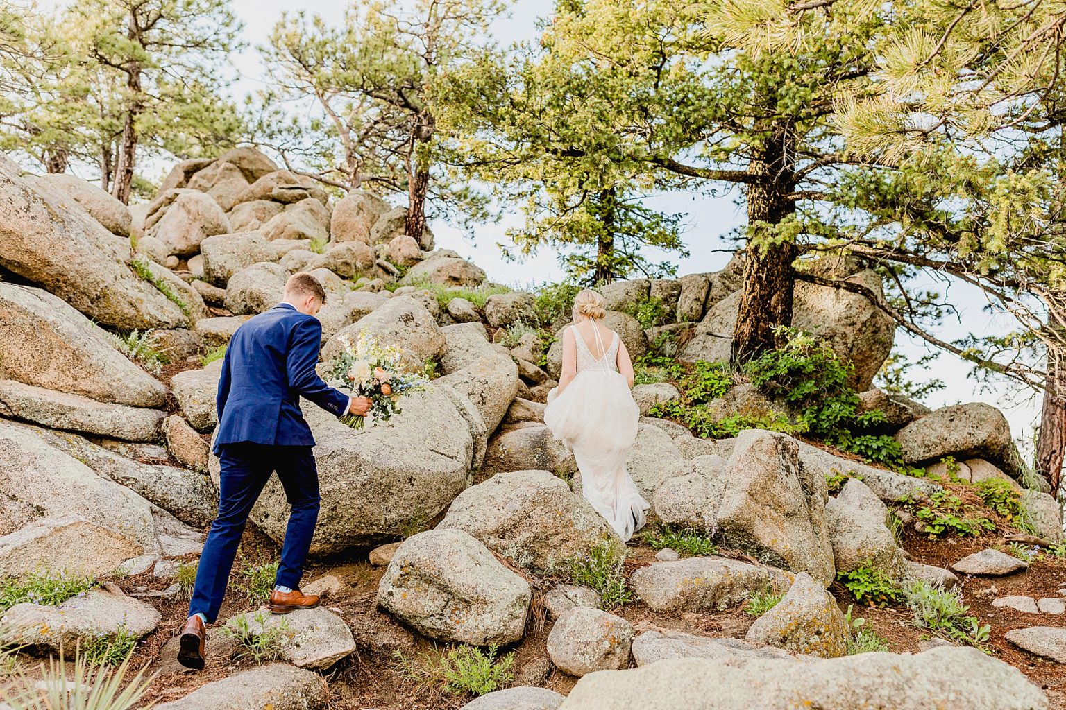 bride and groom climb up rocks for sunset photos
