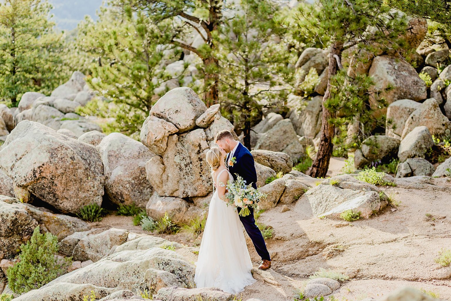 bride and groom kiss with gorgeous views of the boulder rocks and trees