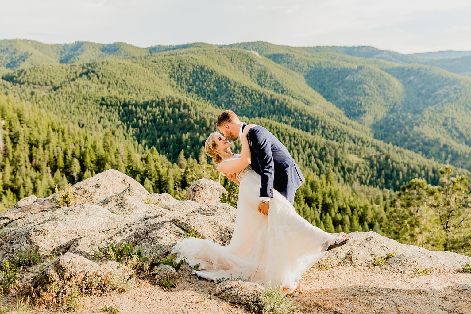 groom dips his bride with stunning Rocky Mountain colorado background