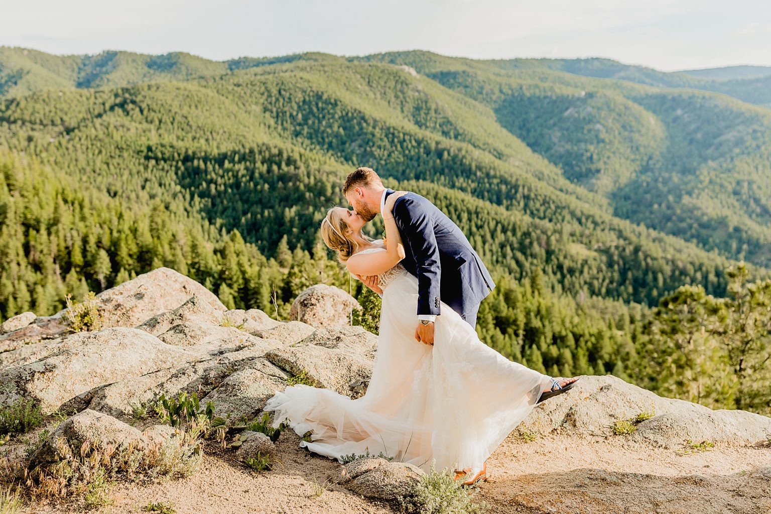 groom dips his bride with stunning Rocky Mountain colorado background