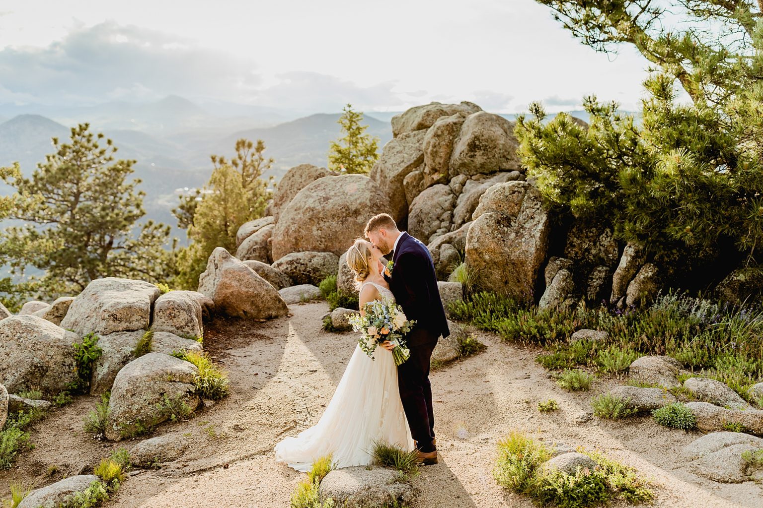 newlywed couple kissing with rock and mountain backdrop of boulder colorado