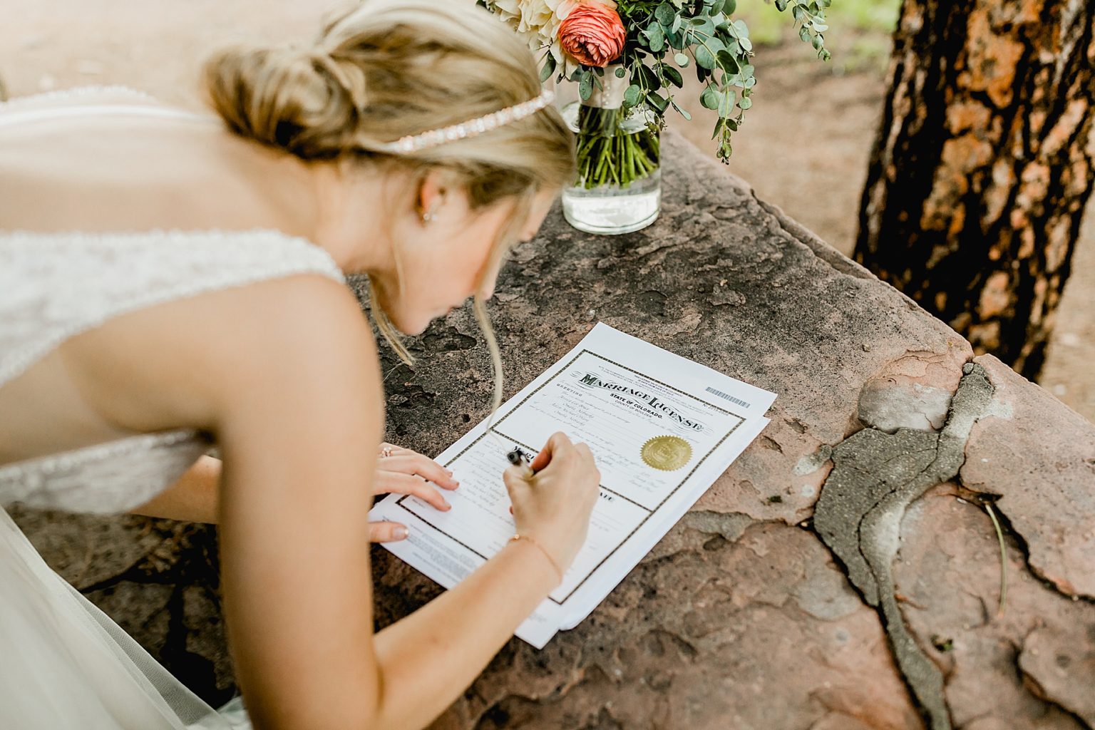 bride signs the marriage certificate outside