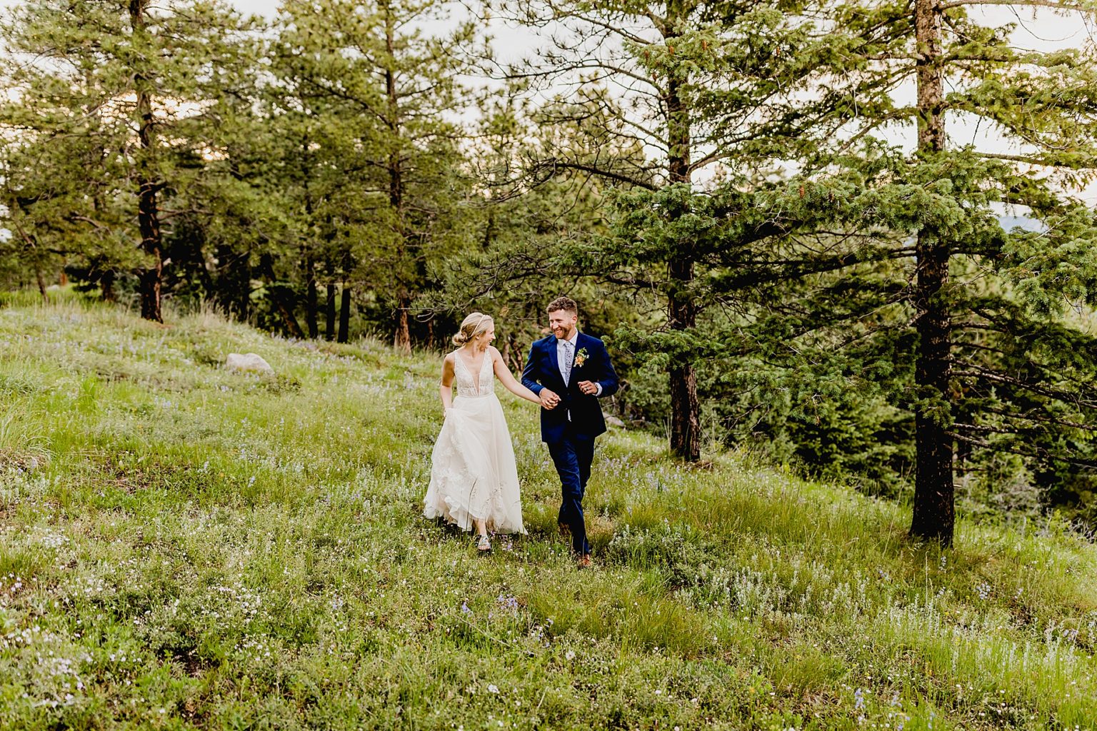 bride and groom hold hands and run together in beautiful boulder colorado forest on flagstaff mountain