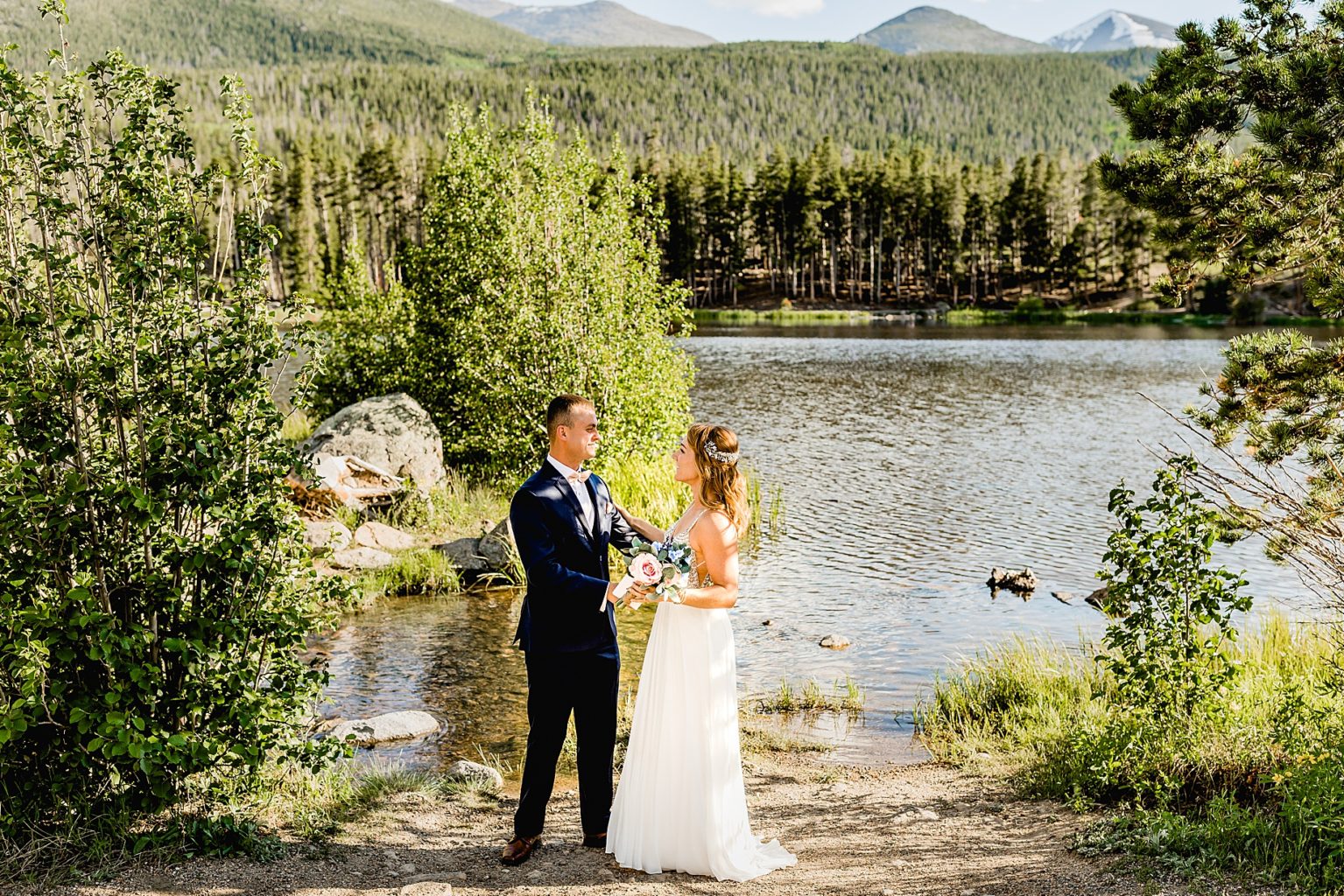 bride and groom share first look together next to beautiful trees and lake