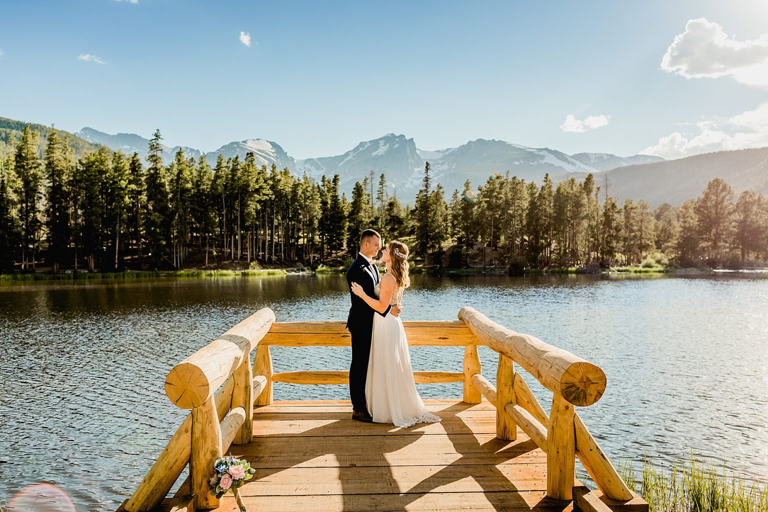 bride and groom on colorado wedding deck at Sprague Lake with beautiful mountain and water background