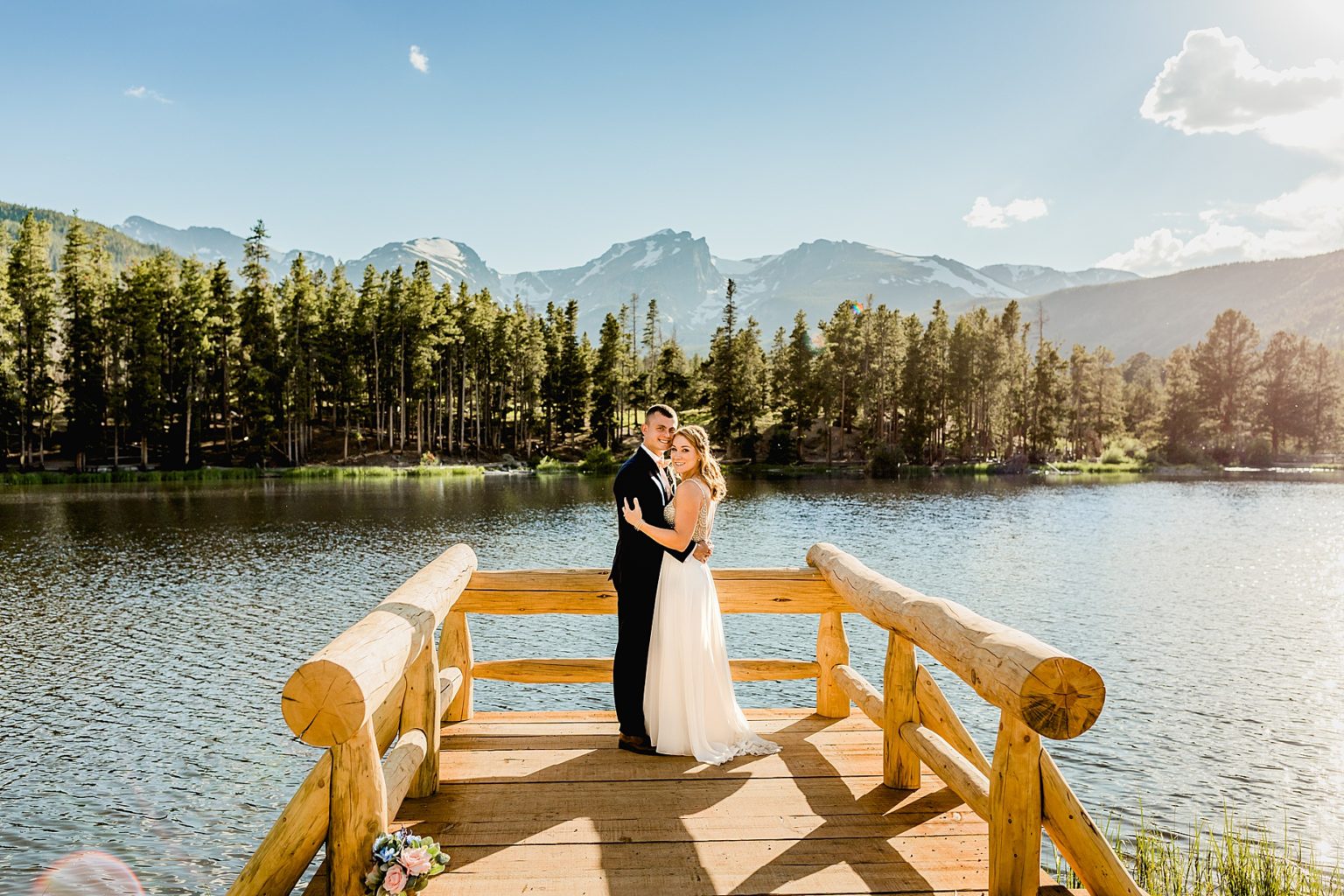 bride and groom on colorado wedding deck at Sprague Lake with beautiful mountain and water background