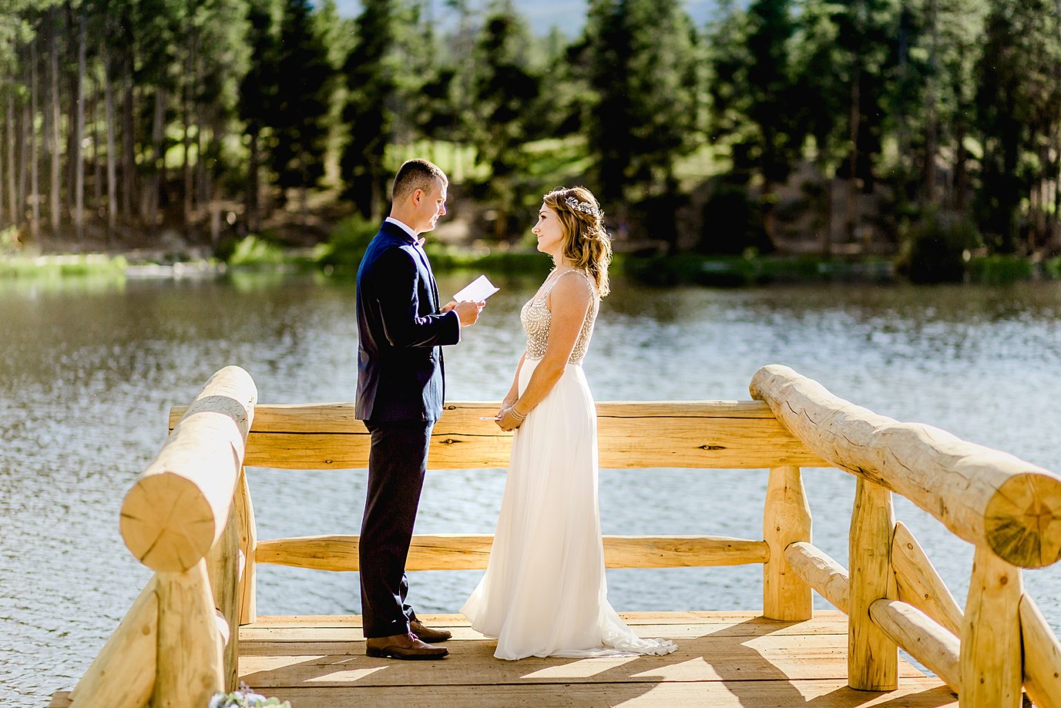 bride and groom exchange vows Sprague Lake in Rocky Mountain national park on a beautiful summer day with gorgeous mountain views in the background