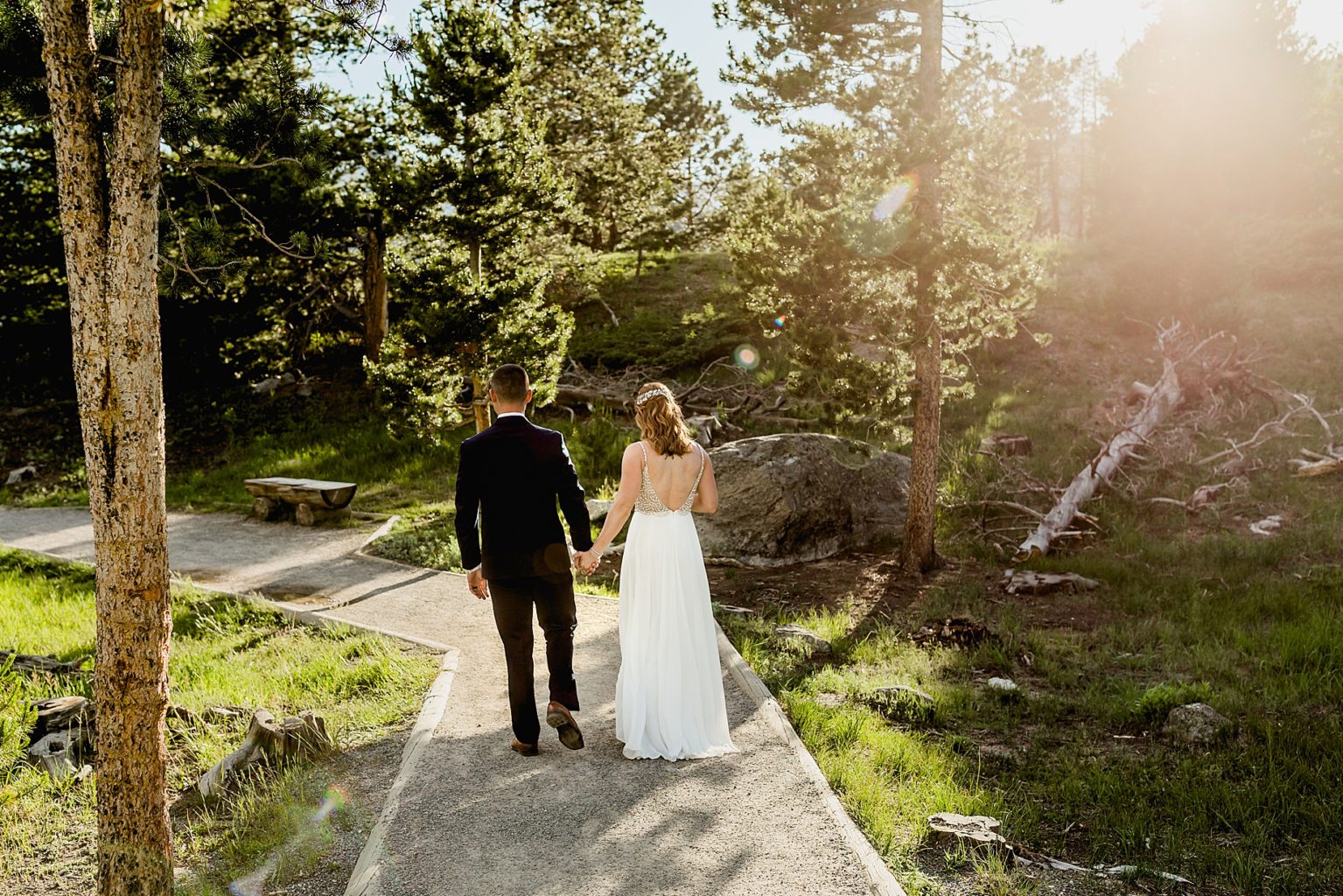 bride and groom walk together after Sprague Lake ceremony in the beautiful trees at sunset