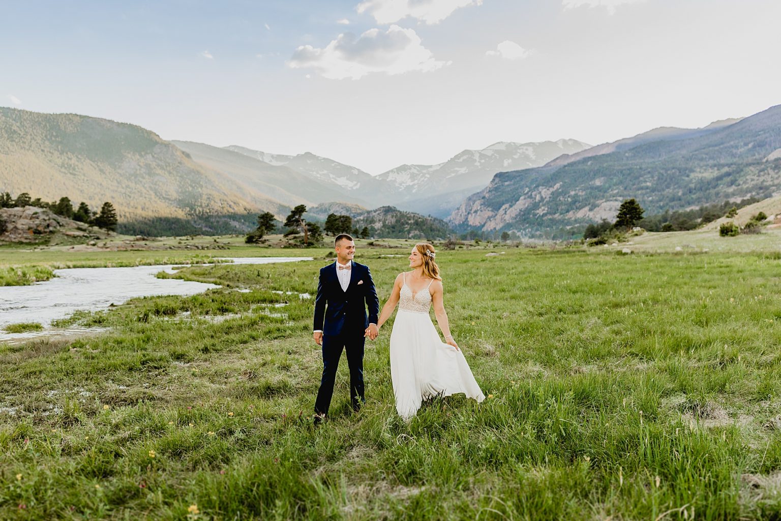 bride and groom holds hands in beautiful Estes Park at sunset after their elopement in moraine park