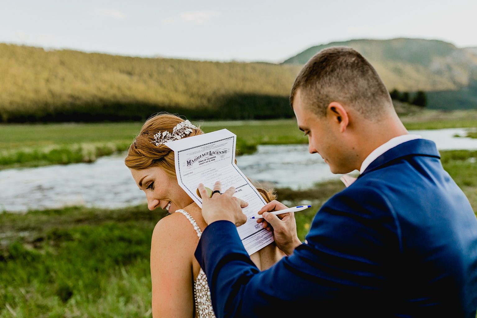 groom signs marriage certificate on brides back in colorado