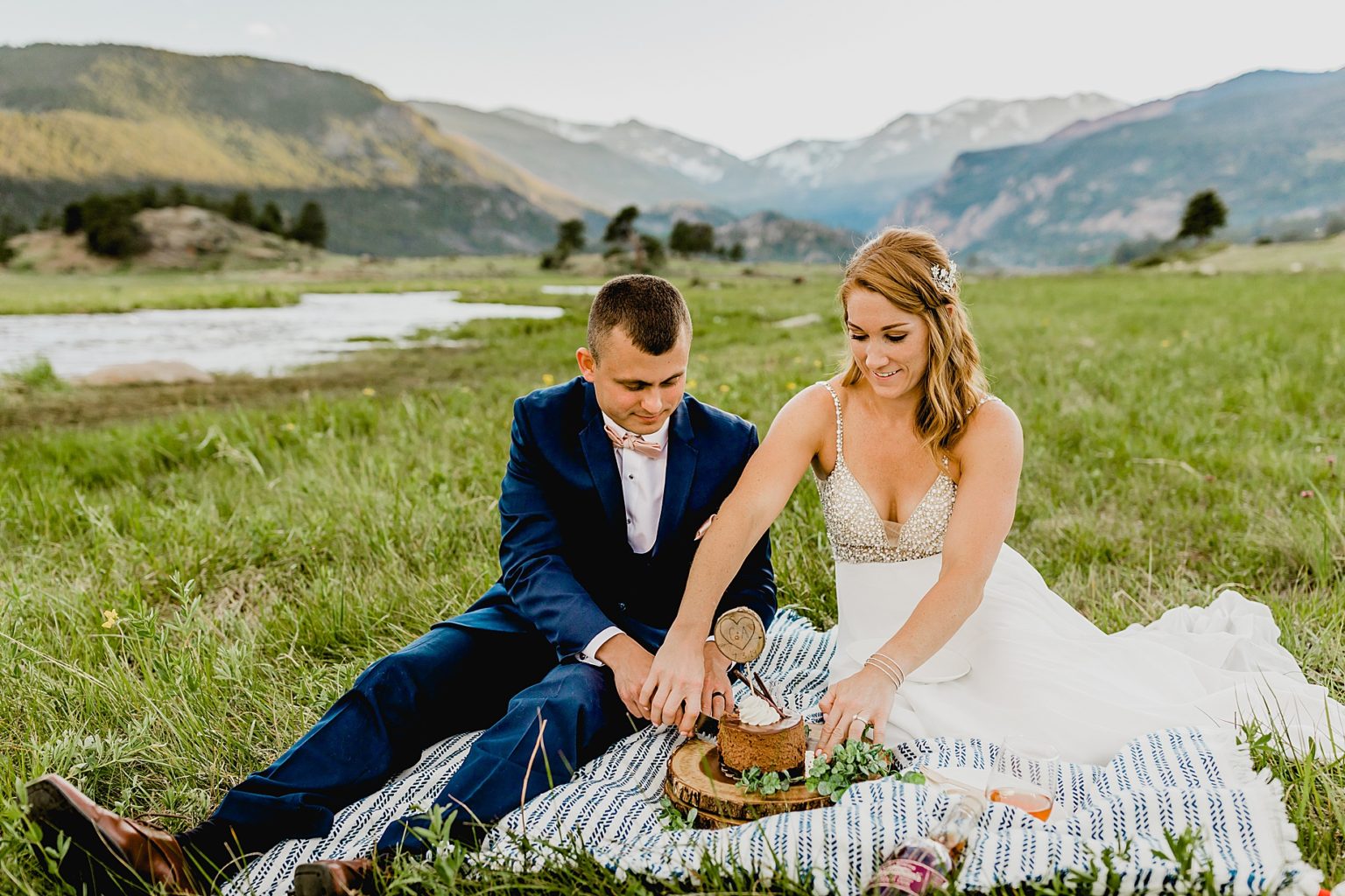 bride and groom cut into little wedding cake with colorado backdrop
