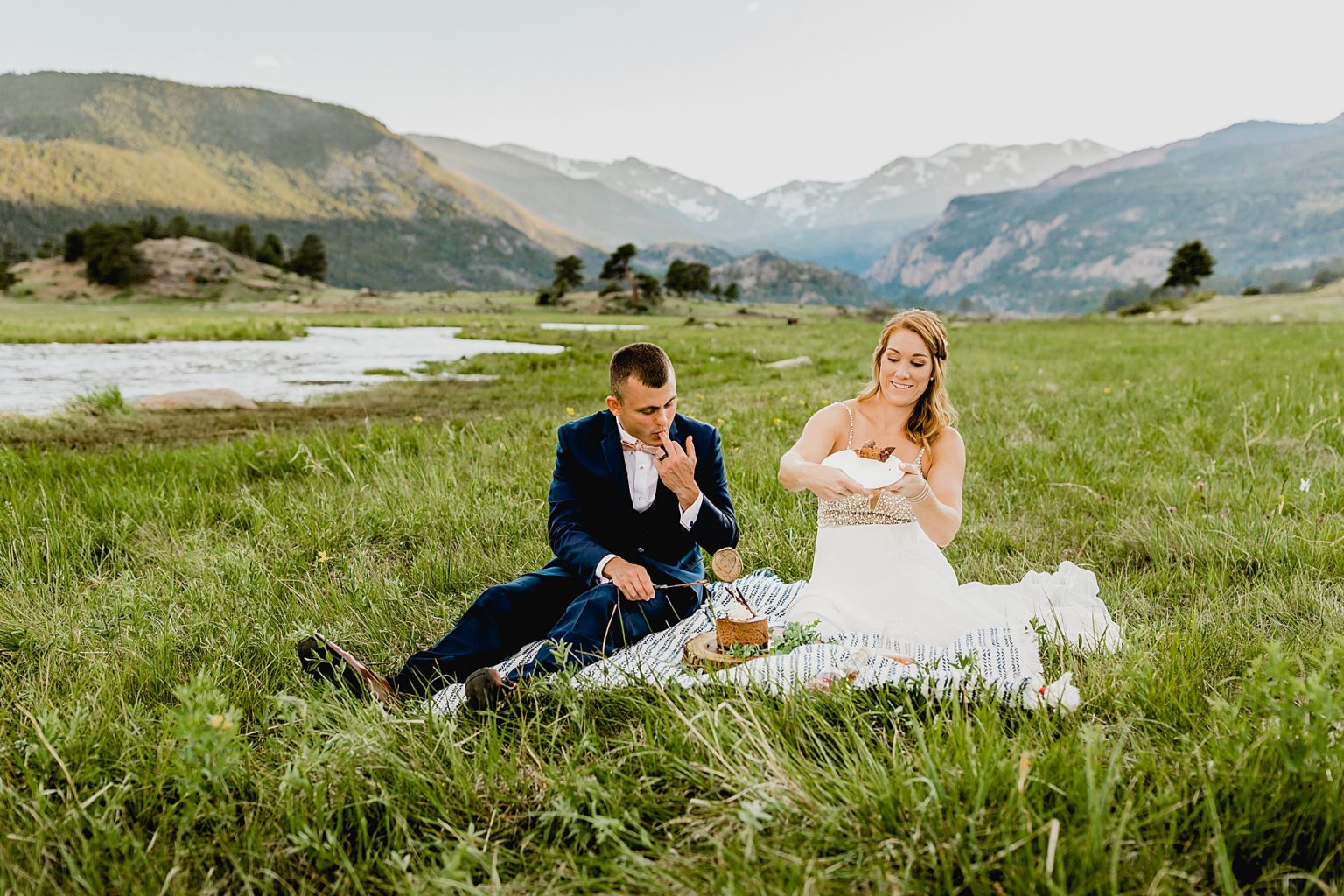 bride and groom eat wedding cake with colorado backdrop