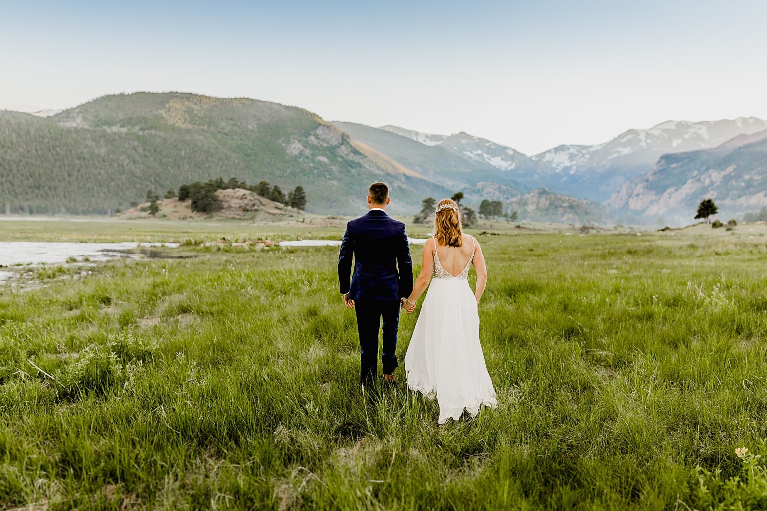 bride and groom hold hands in beautiful colorado mountain scenery in rmnp