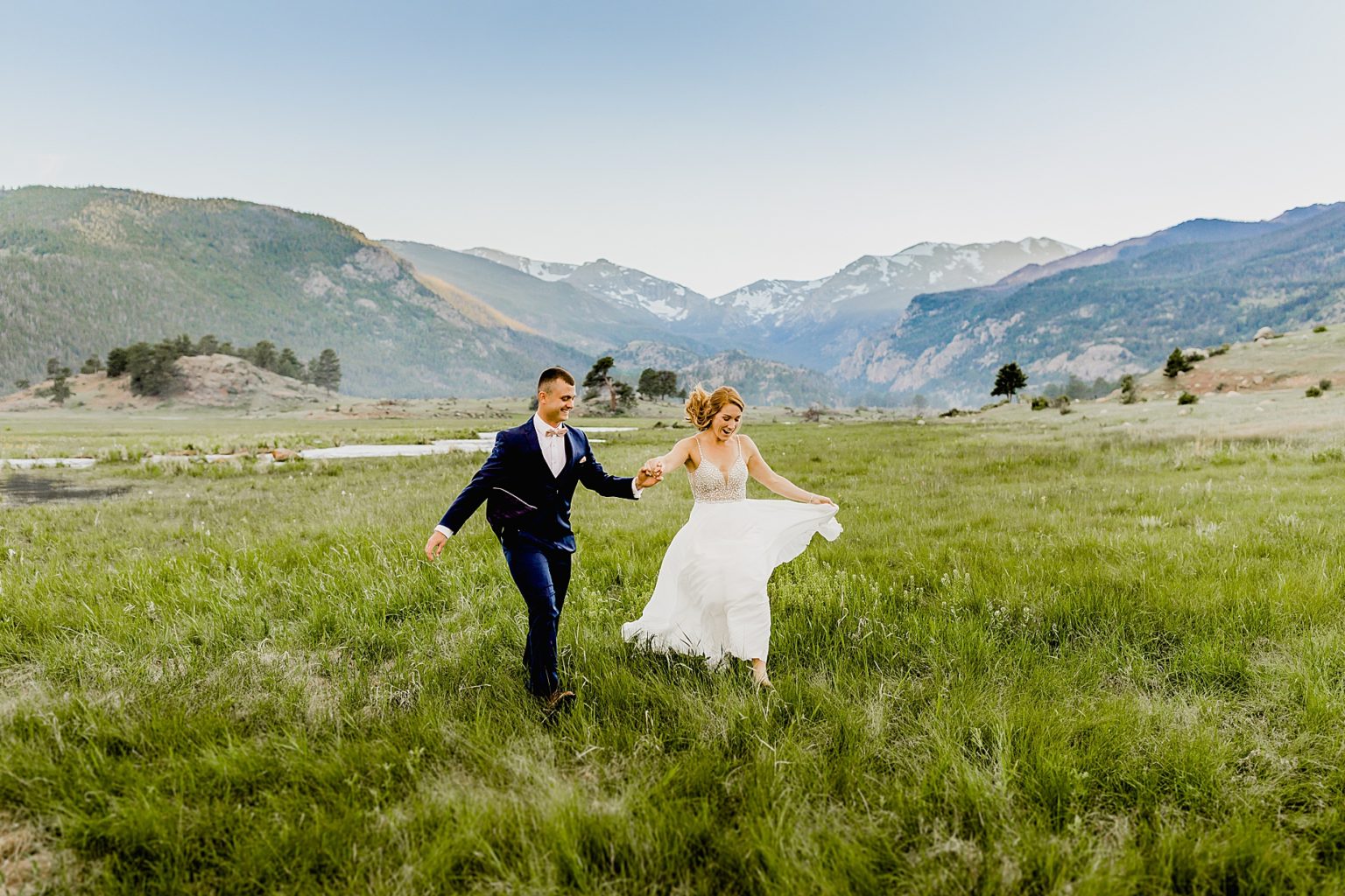 bride and groom hold hands in beautiful colorado mountain scenery in rmnp