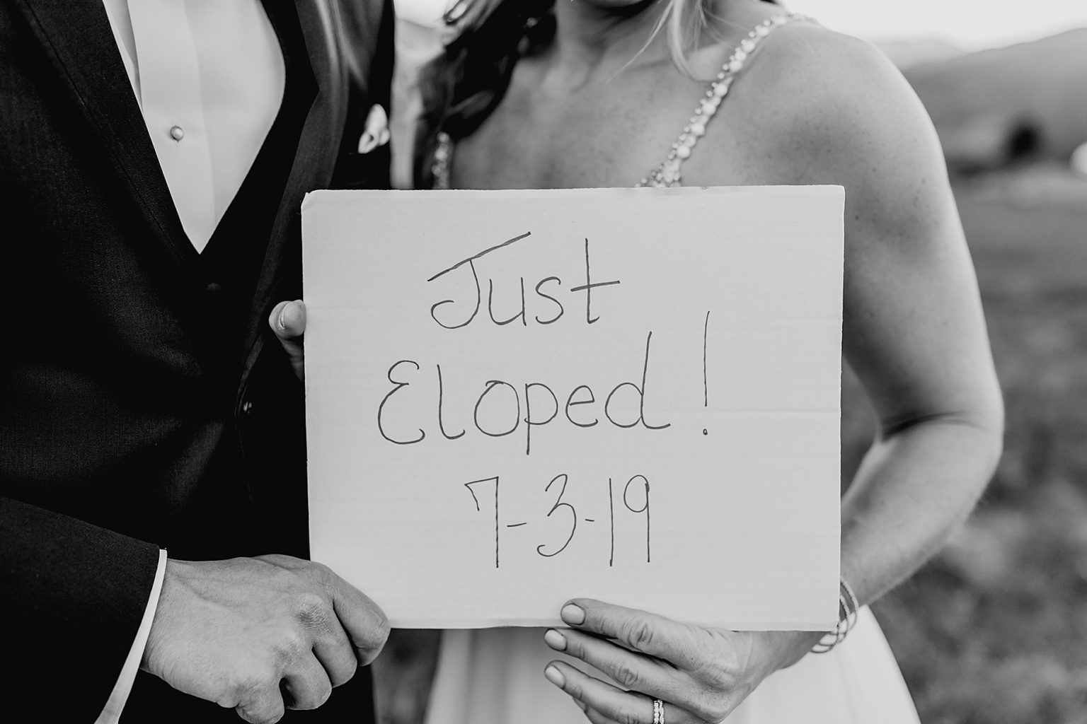 bride and groom hold up just eloped sign