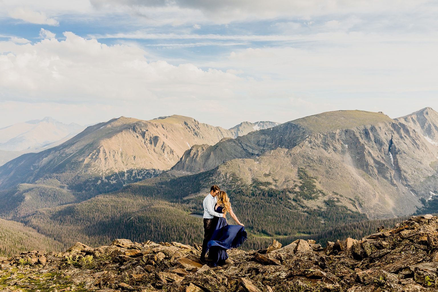 couple hugging in the beautiful Rocky Mountains and woman twirls her flowy dress