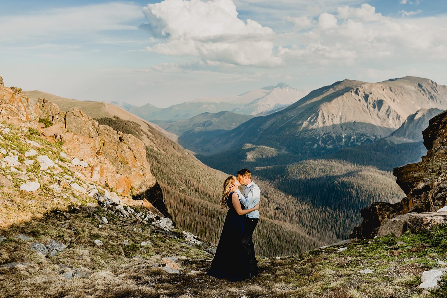 couple embraces for a kiss with stunning Rocky Mountain backdrop