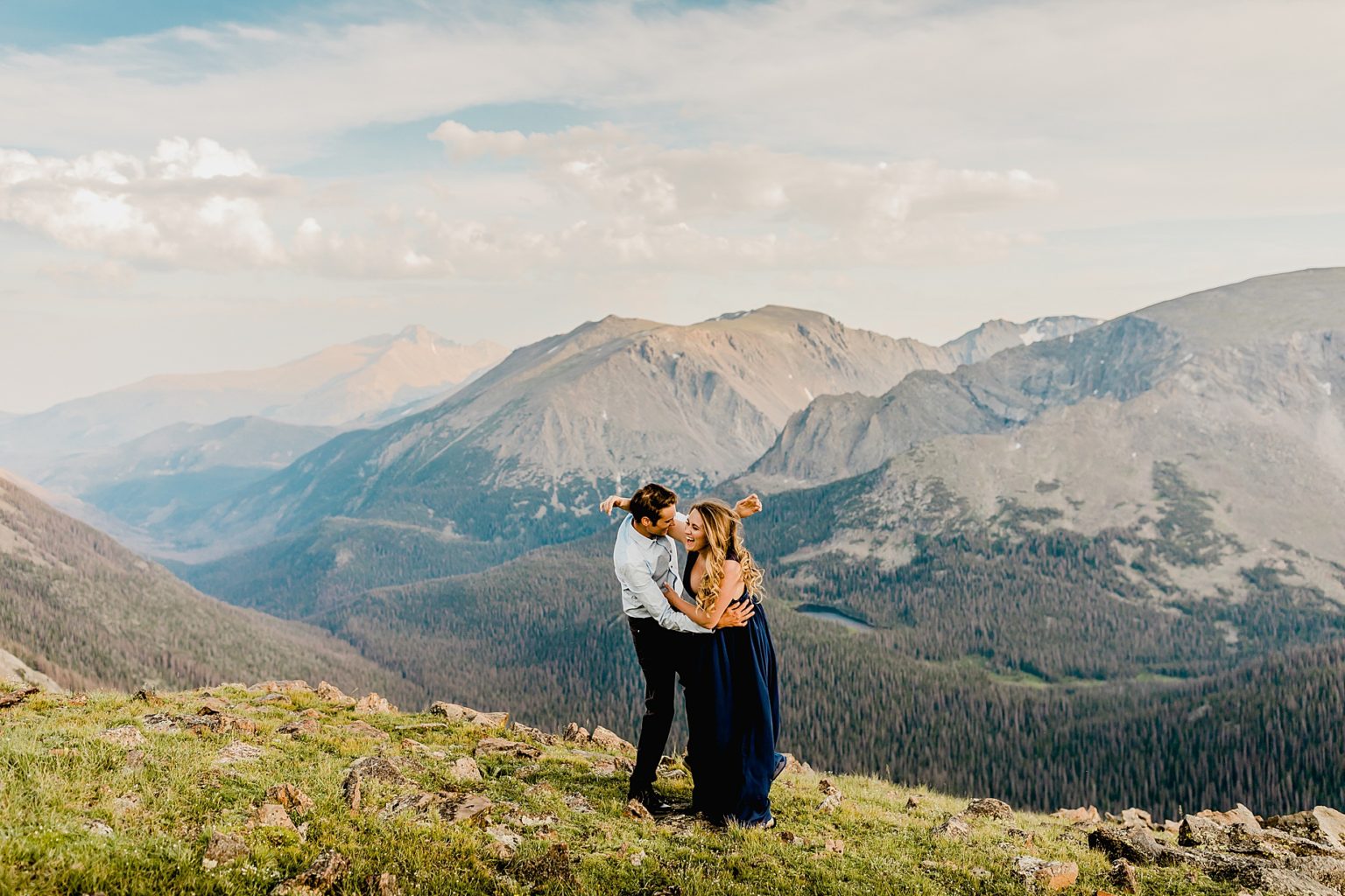 couple spins and dances together at sunset with gorgeous Rocky Mountain scenery showing the amazing pink and blue sunset colors