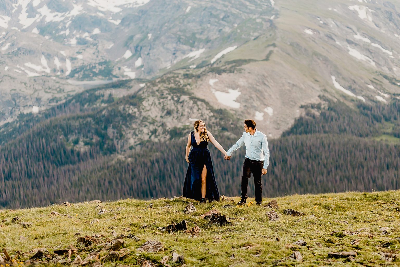 couple holds hands with gorgeous Rocky Mountain national park mountain scenery