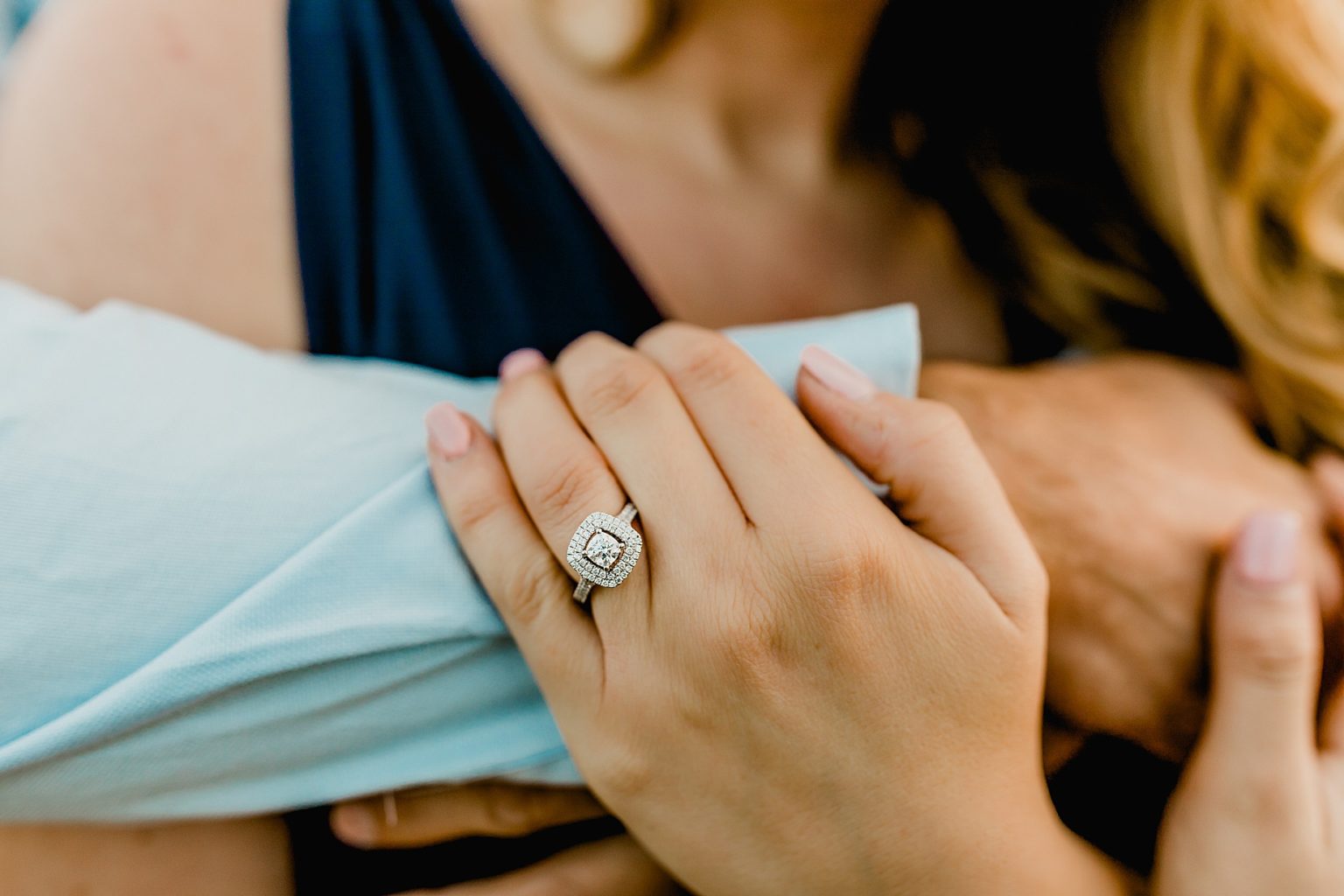 woman's engagement ring is shown while holding onto partners arm
