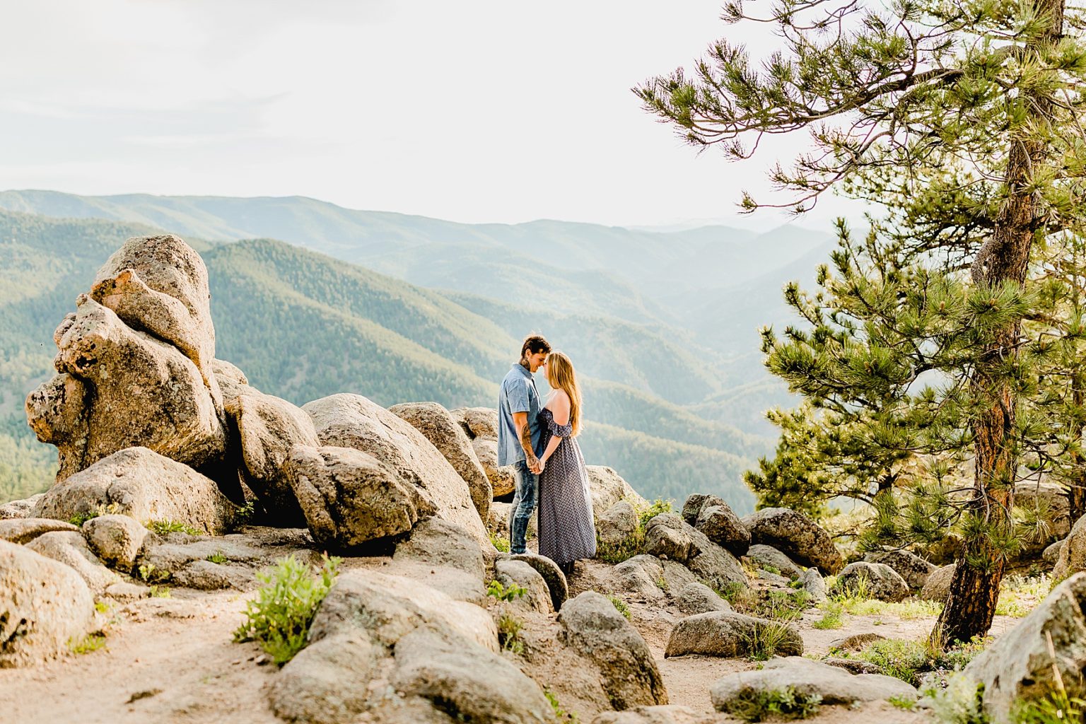 couple holds hands with beautiful mountain scenery surrounded by boulder rocks