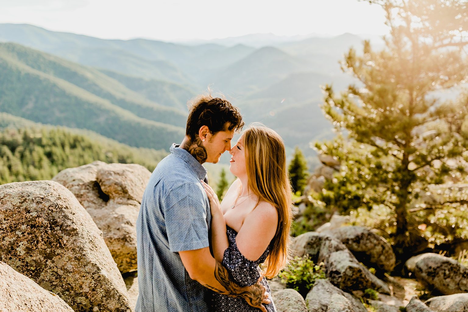 couple holds each other with gorgeous colorado mountain backdrop at sunset surrounded by trees