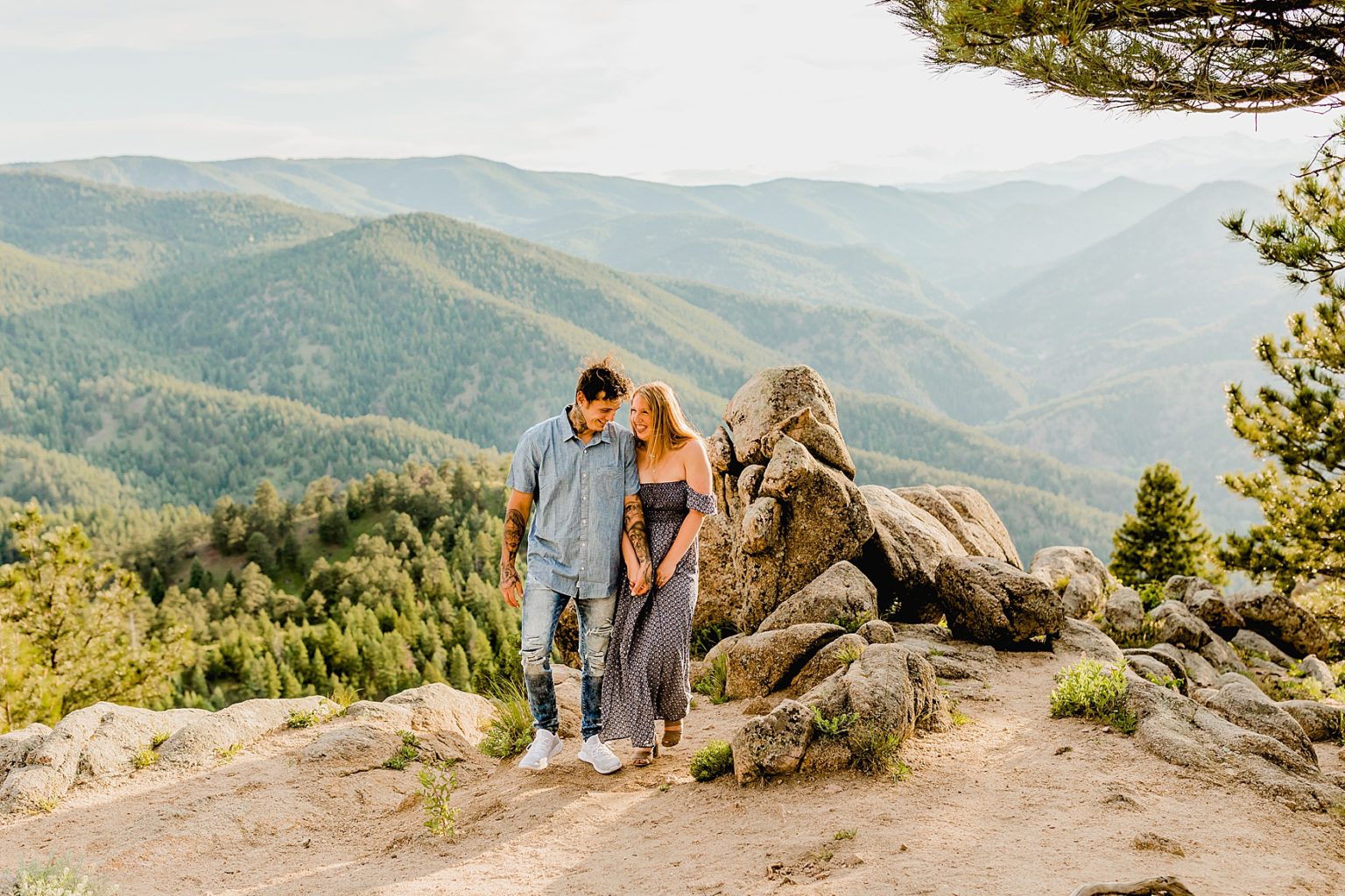 couple walks together laughing with gorgeous colorado mountain background in the summer