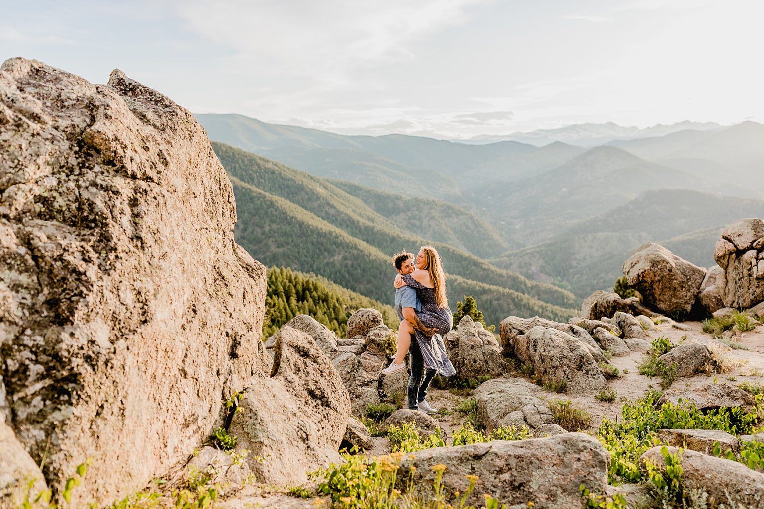 couple embraces together for engagement session with beautiful boulder colorado scenery showing off the trees and mountains