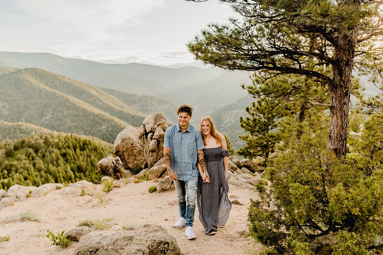 couple holds hands and laughs together with incredible mountain backdrop