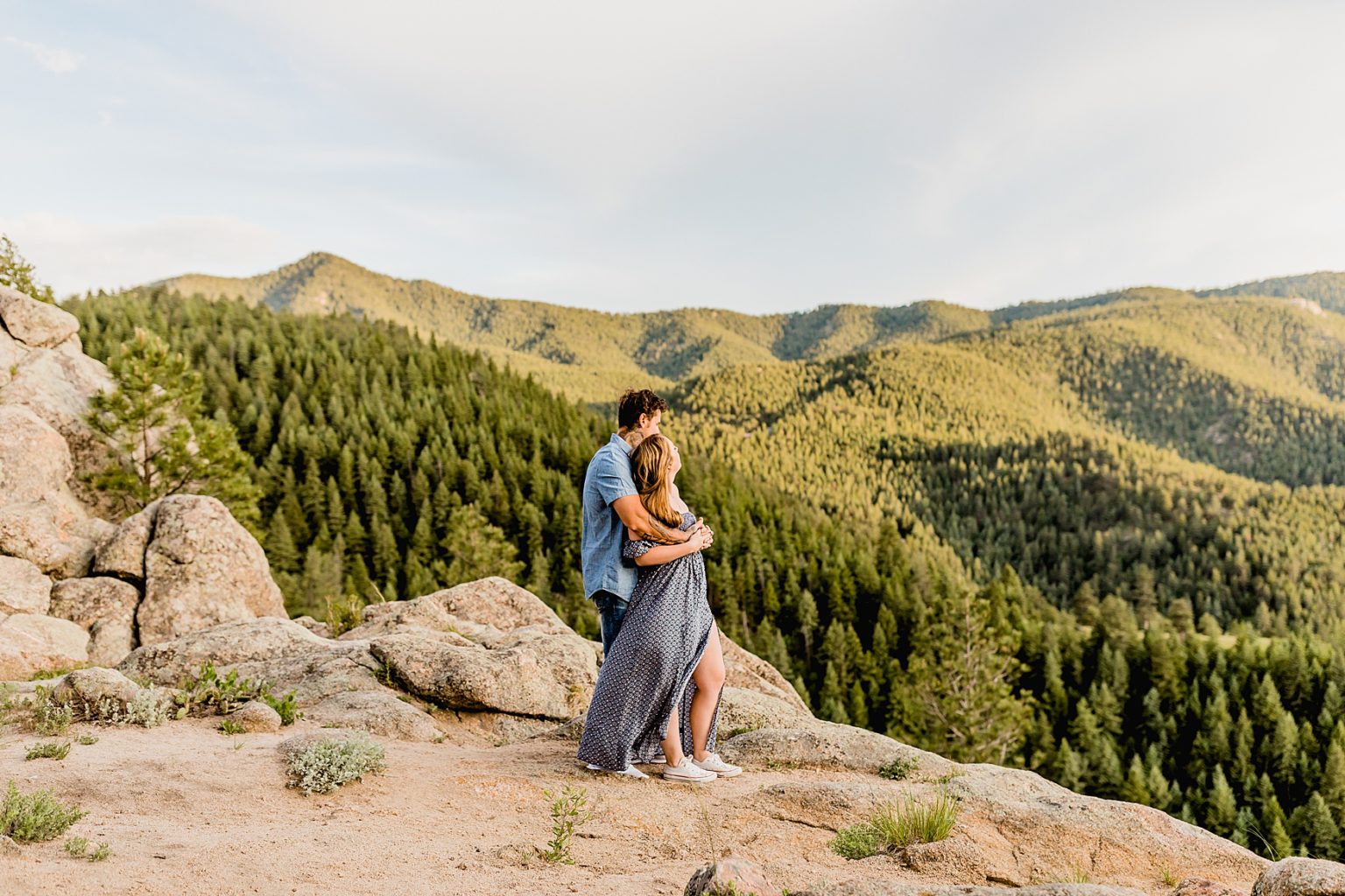 man hugs woman and they look out at the wonderful mountain scenery surrounding them