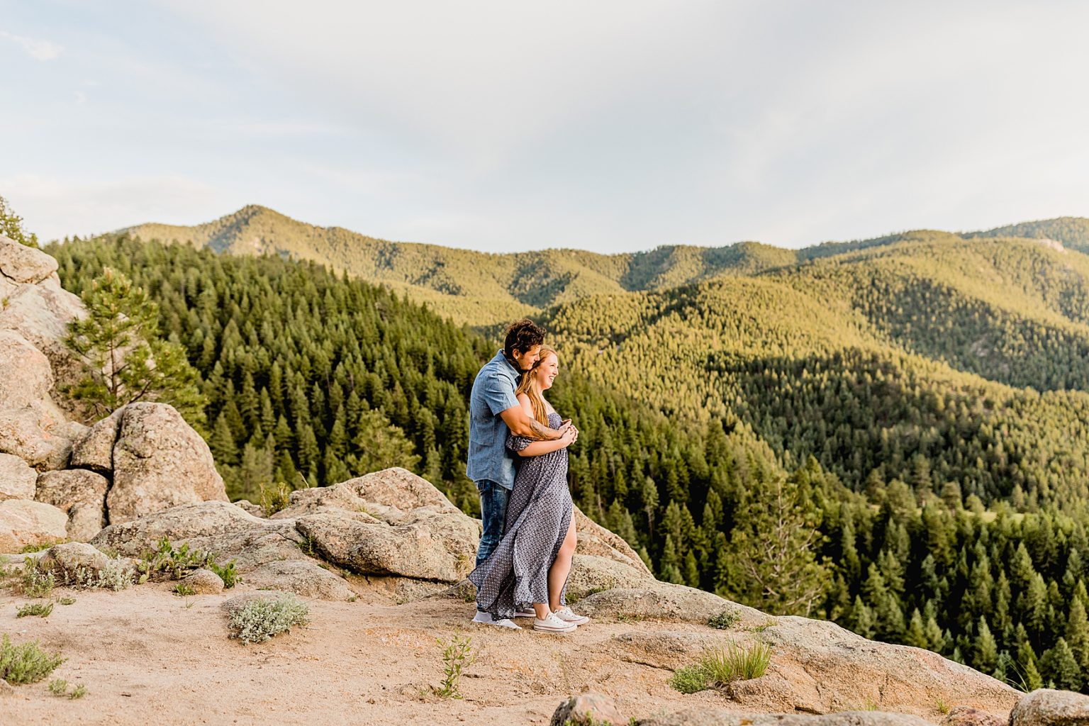 man hugs woman and they look out at the wonderful mountain scenery surrounding them