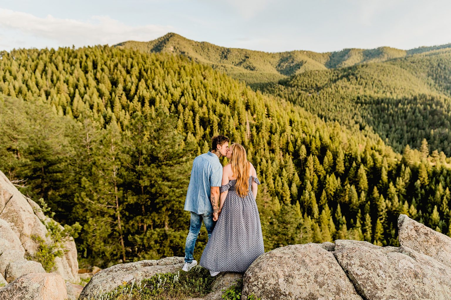 couple holds hands and they look out at the wonderful mountain scenery surrounding them