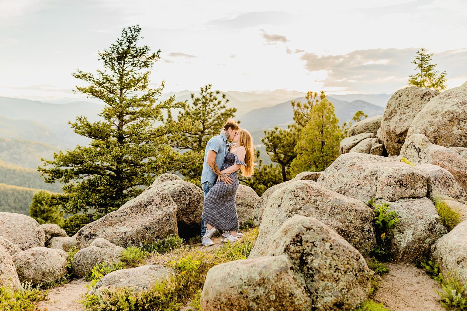 couple holds each other and has a lot of fun while being surrounded by stunning green trees and colorado mountains for adventure engagement photos