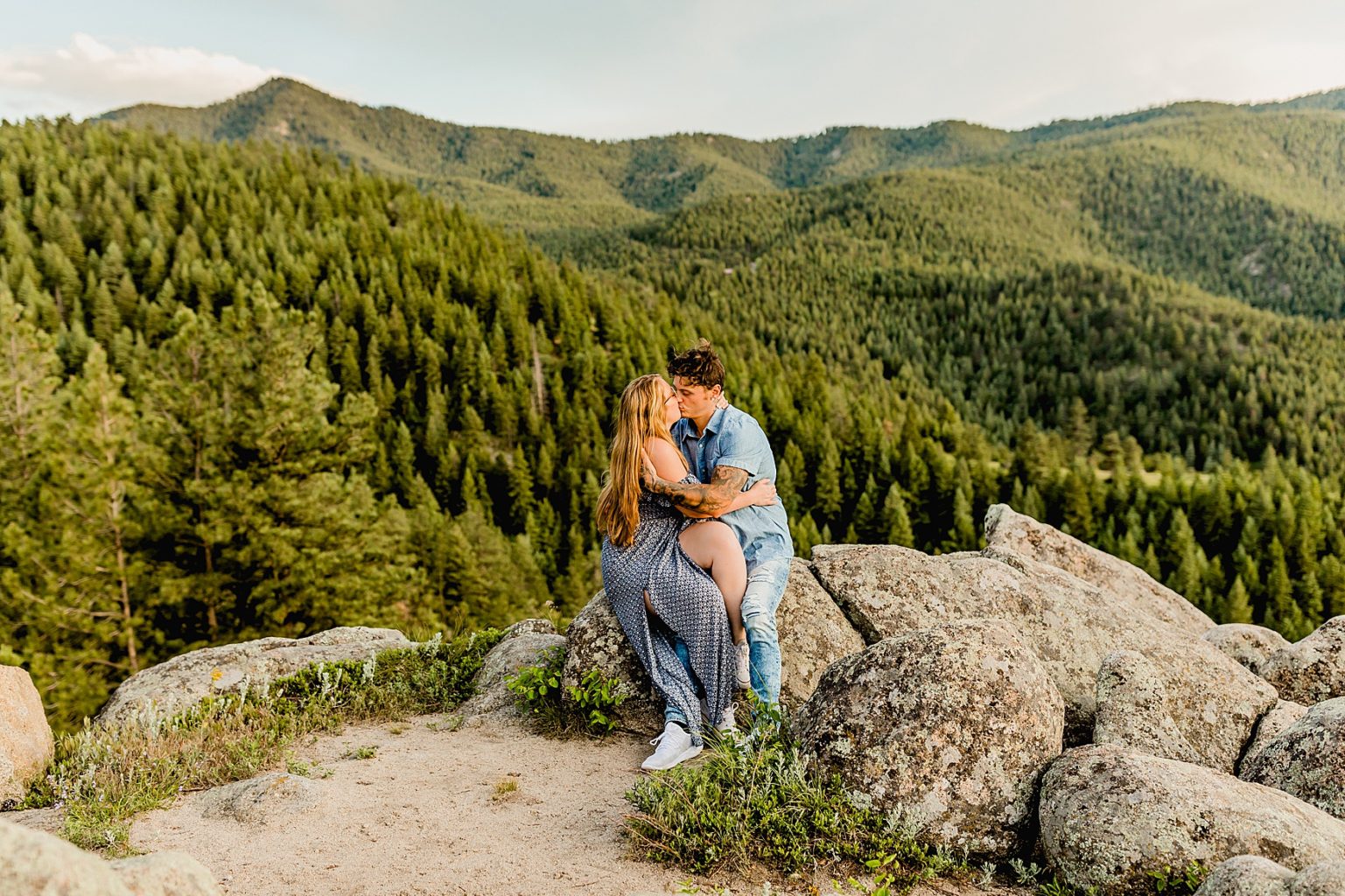 couple sits on rocks while embracing each other in the beautiful colorado mountain scenery