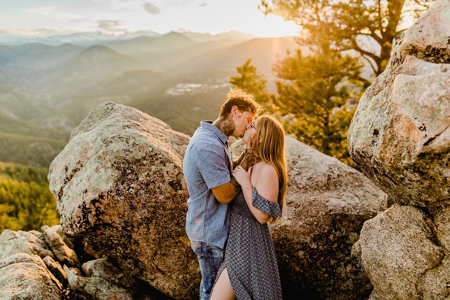 couple holds each other next to rock formations with beautiful colorado sunset and mountain background for adventure engagement session
