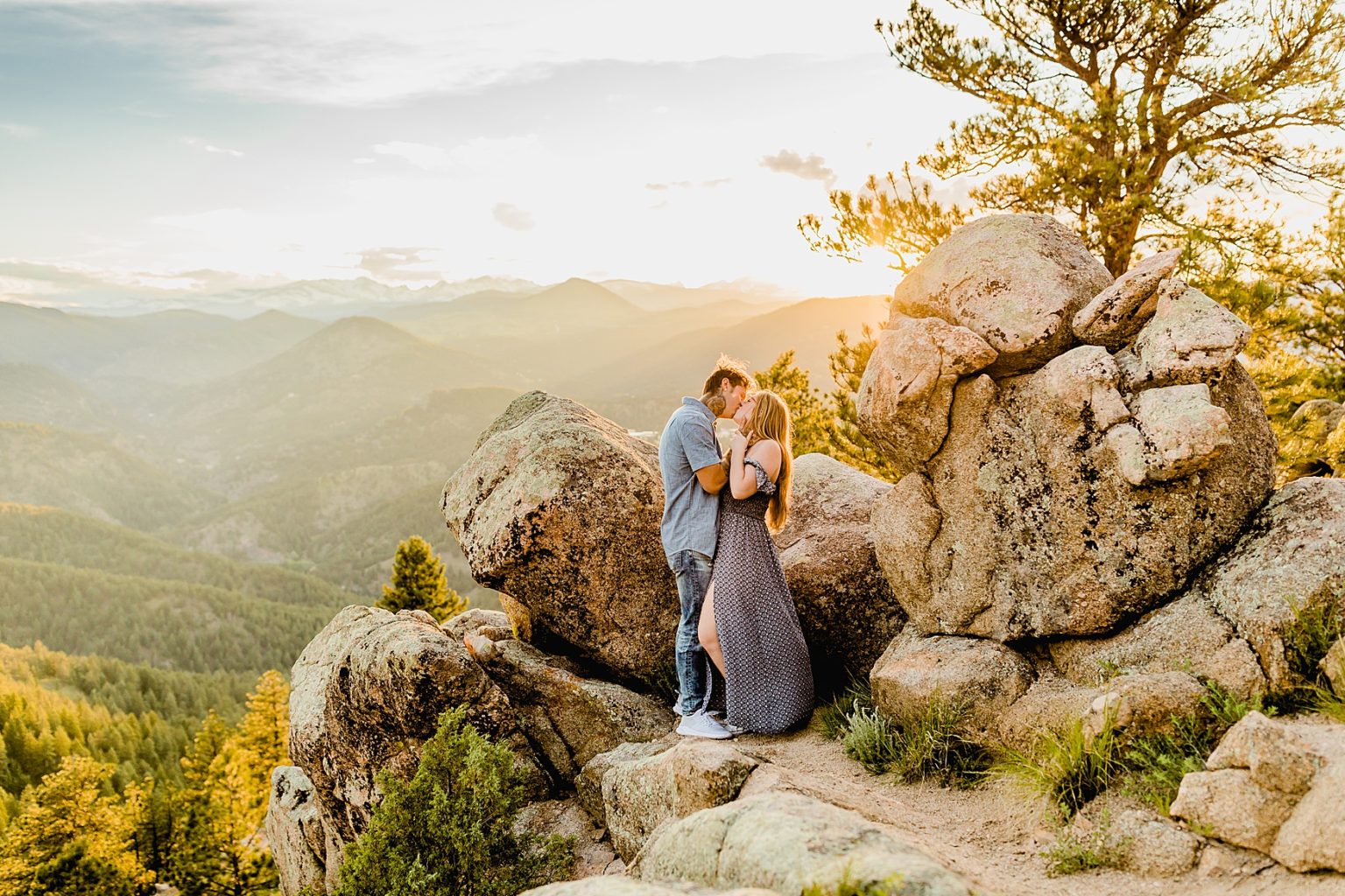 couple holds each other next to rock formations with beautiful colorado sunset and mountain background