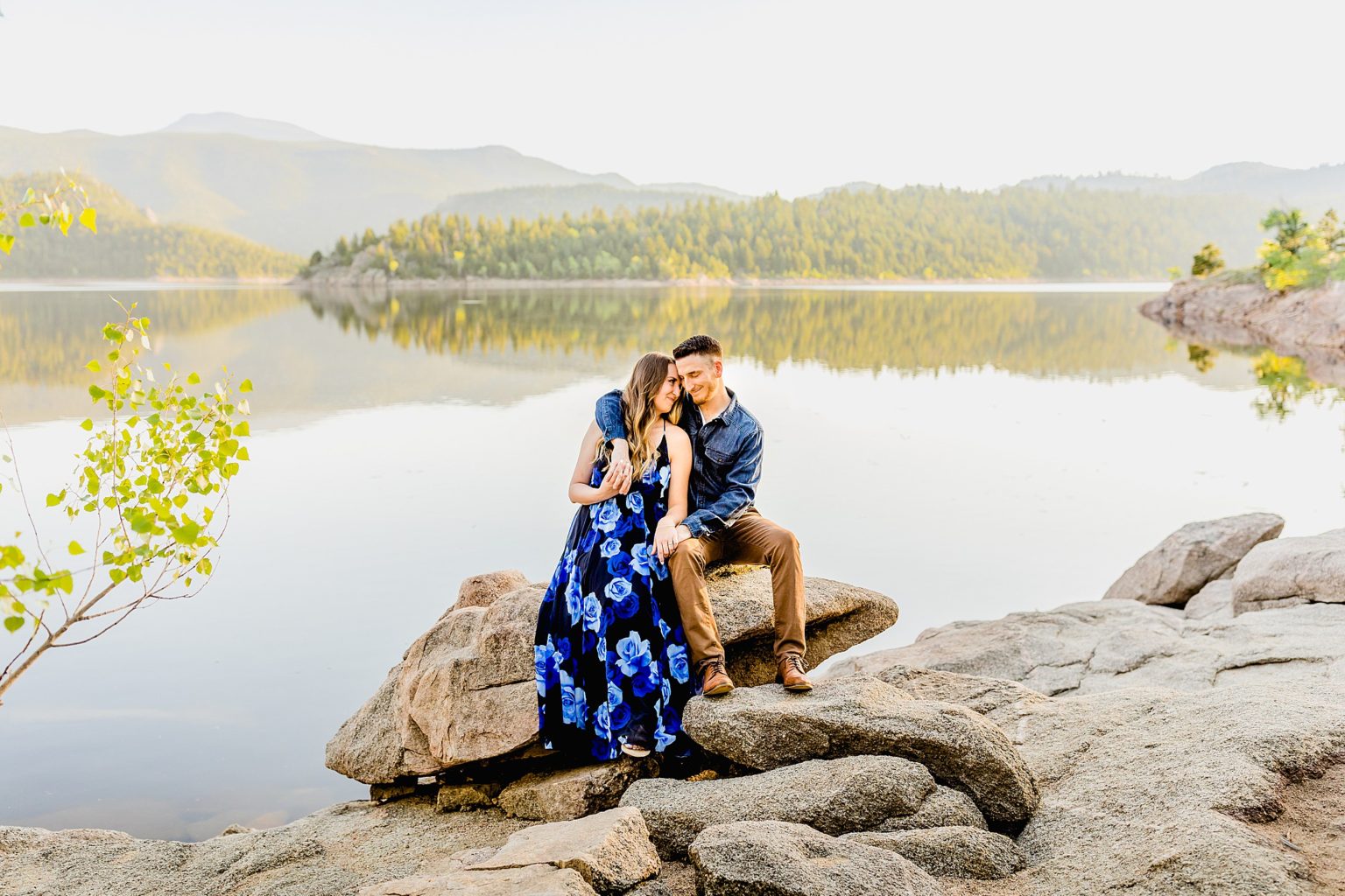 couple sits on rocks in front of beautiful boulder colorado lake with gorgeous mountain scenery