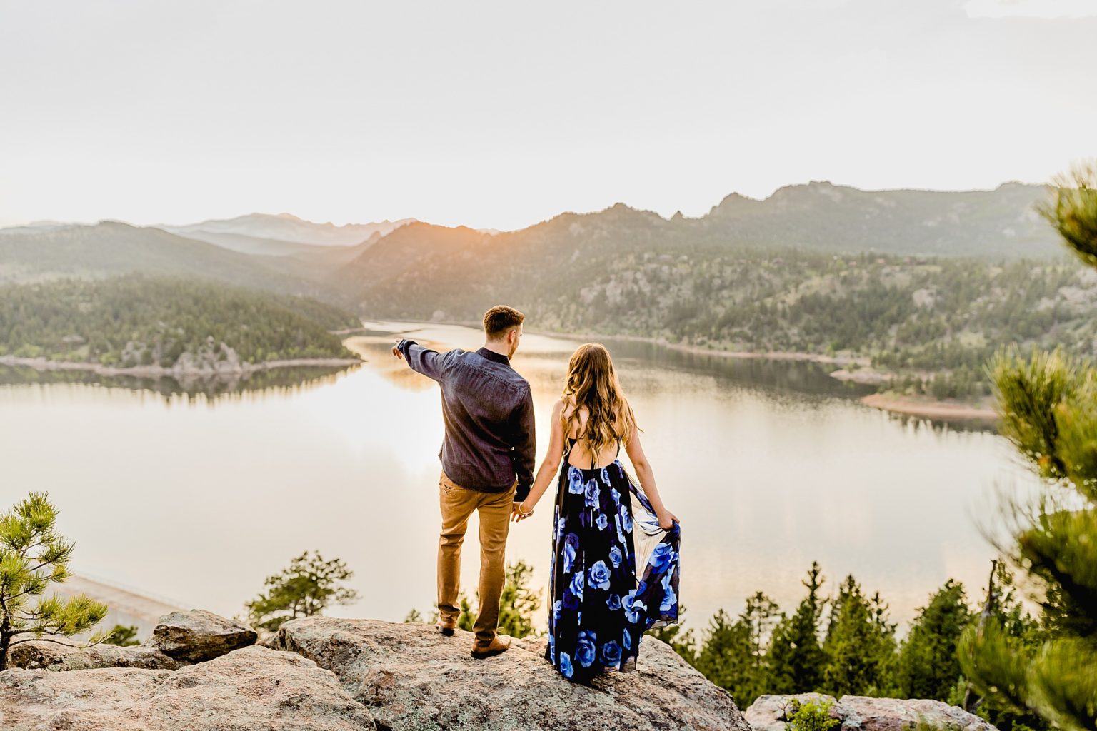 couple stands together overlooking incredible rocky mountain scenery and lake to celebrate anniversary