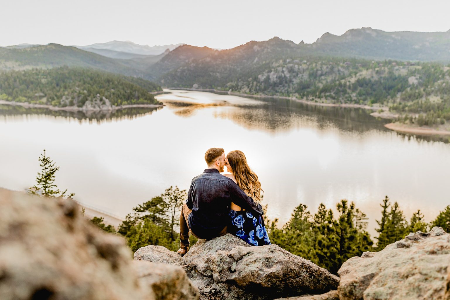 couple sits together overlooking incredible rocky mountain scenery and lake to celebrate anniversary
