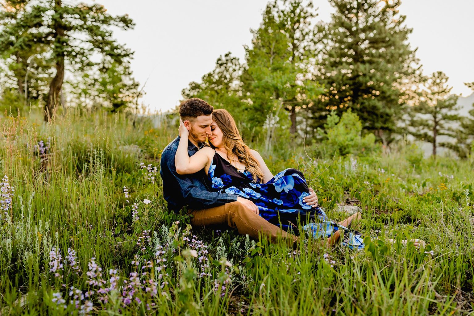 couple sits in wildflowers in gorgeous boulder colorado location surrounded by greenery and mountains