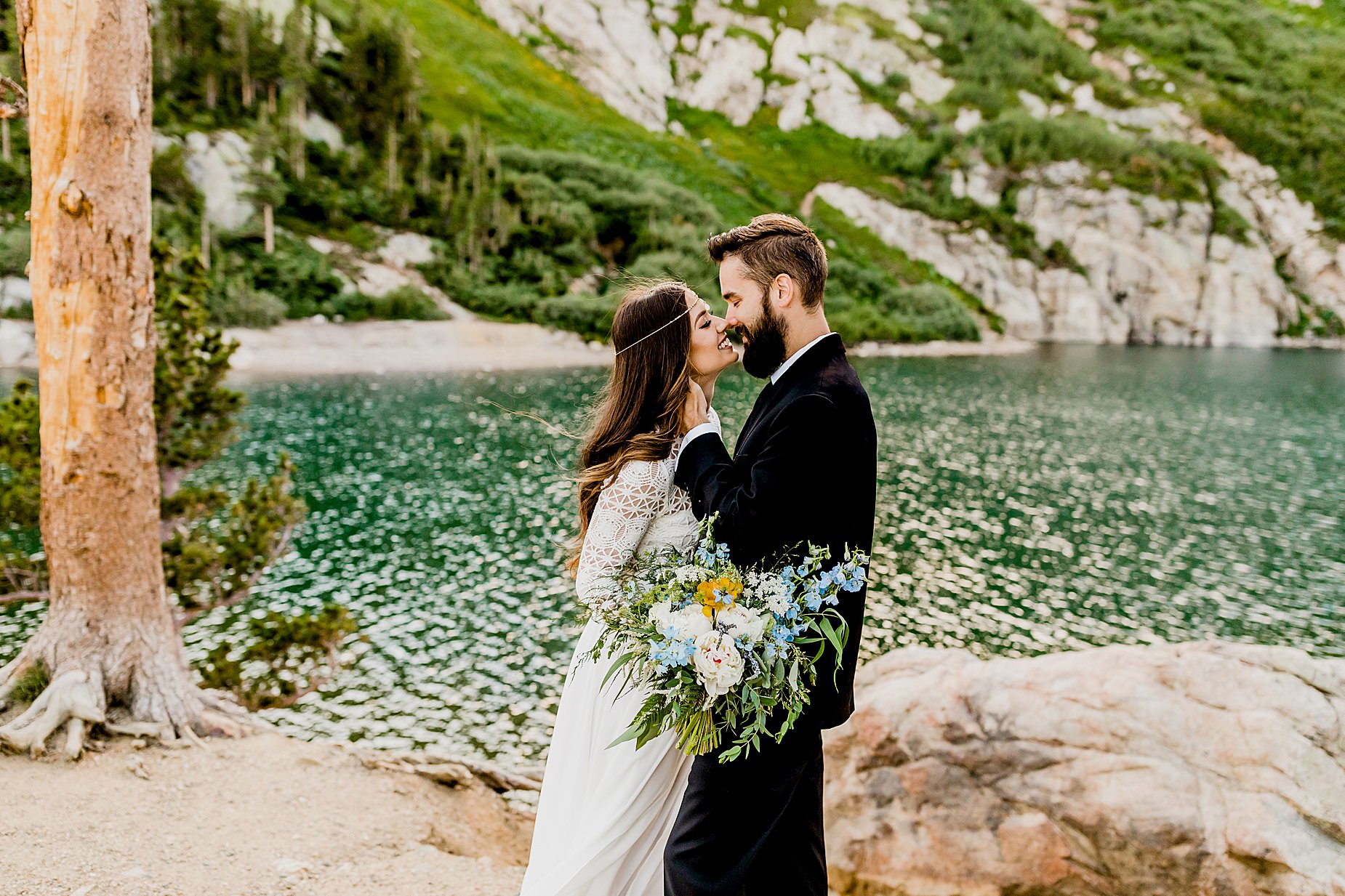bride and groom embrace in front of beautiful colorado alpine lake for their elopement
